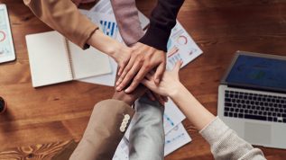 Multiple people put their hands together in a circle